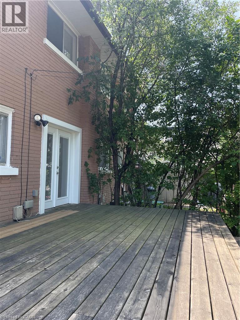 Wood-plank outdoor deck with double glass-pane doors, brick exterior, and mature trees - 124 Avalon Place, Kitchener, ON