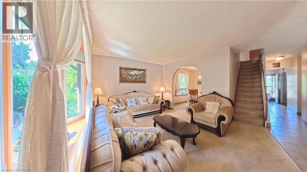 Bay window with sheer drapery, arched doorway, and carpeted flooring - 56 Scenic Wood Crescent, Kitchener, ON