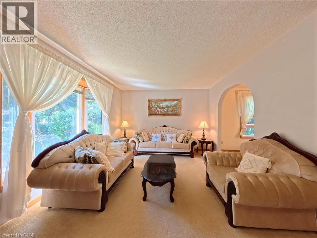Spacious living area with large windows, an arched doorway, and soft wall colors - 56 Scenic Wood Crescent, Kitchener, ON