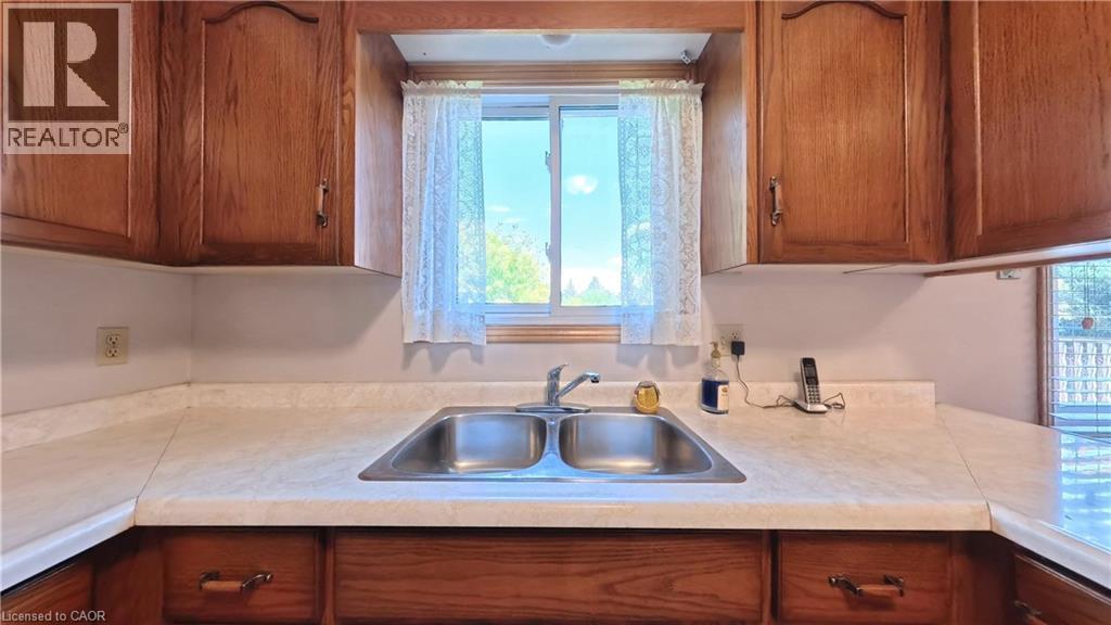 Double basin stainless steel sink with a chrome faucet, set into a light-toned countertop - 56 Scenic Wood Crescent, Kitchener, ON