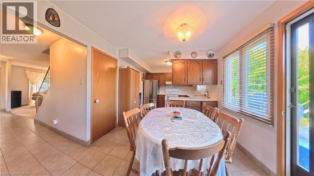 Kitchen with wood cabinetry, stainless steel appliances, and a window with blinds - 56 Scenic Wood Crescent, Kitchener, ON
