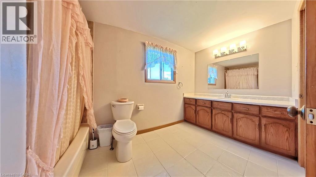 White tile flooring with a light-colored vanity featuring a lengthy countertop and dual sinks - 56 Scenic Wood Crescent, Kitchener, ON