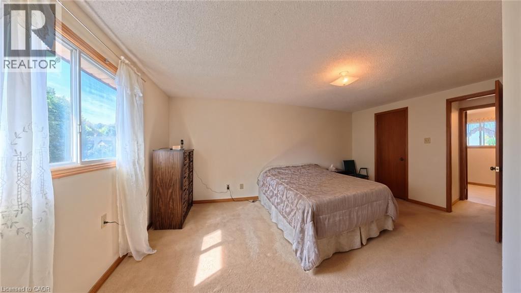 Neutral-toned carpeting, ample natural light from a large window, a ceiling-mounted light fixture, and a solid wood door - 56 Scenic Wood Crescent, Kitchener, ON