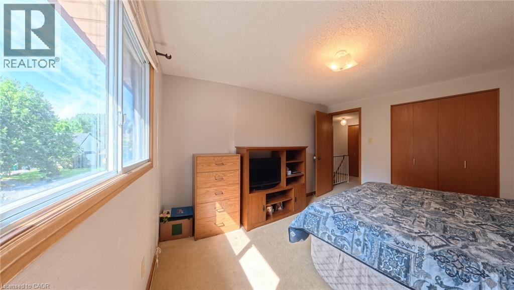 Large windows, ceiling-mounted light fixture, wood-finish bi-fold closet doors, wall-to-wall carpeting, and painted walls - 56 Scenic Wood Crescent, Kitchener, ON