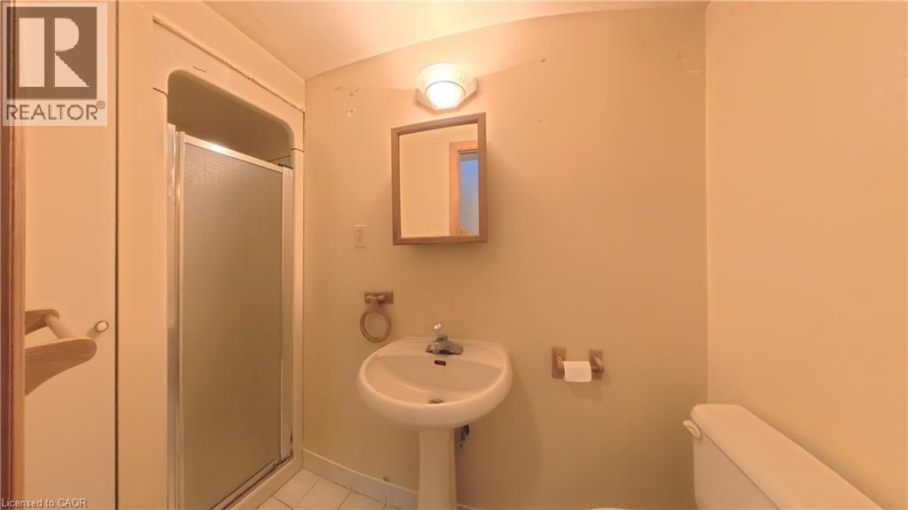 Pedestal sink, wall-mounted mirror, shower enclosure, porcelain toilet, and wall-mounted light fixture - 56 Scenic Wood Crescent, Kitchener, ON