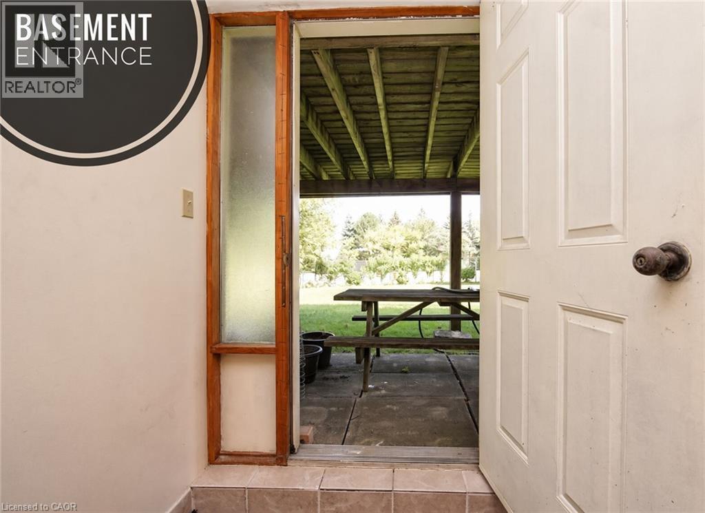 Panel door with a classic knob hardware, wood-framed sidelight, and tiled threshold leading to an exterior covered patio - 56 Scenic Wood Crescent, Kitchener, ON
