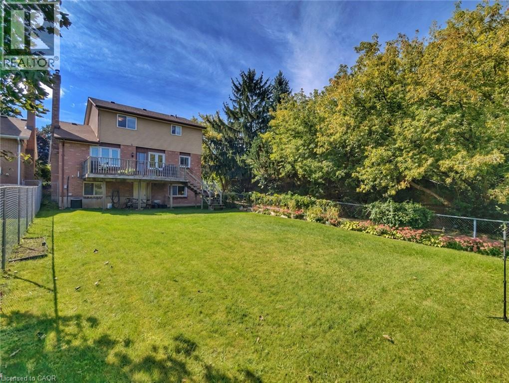 Spacious rear yard with a manicured lawn, established landscaping, and mature trees - 56 Scenic Wood Crescent, Kitchener, ON