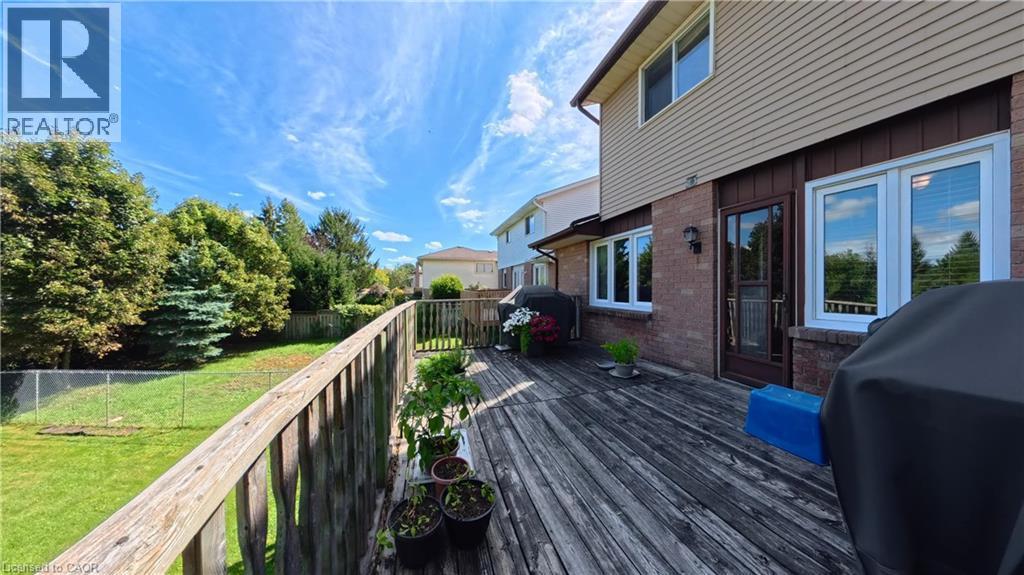 Expansive wooden deck with railing, featuring a brick and siding exterior and multiple windows - 56 Scenic Wood Crescent, Kitchener, ON