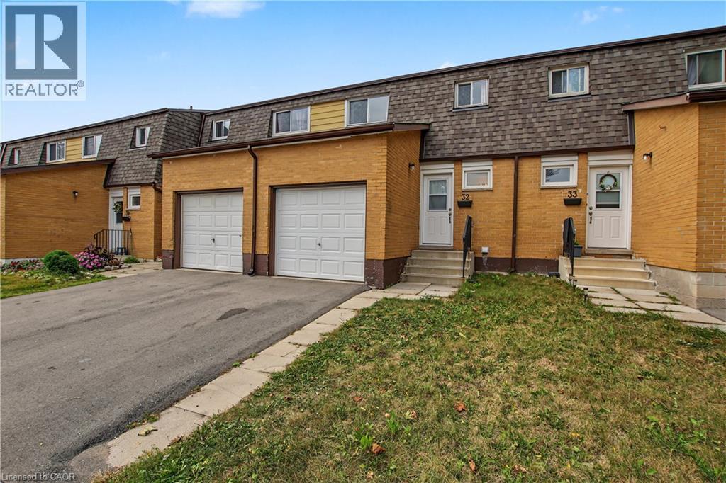 Brick facade townhome with a gambrel roofline, individual garages, and separate entryways - 1444 Upper Ottawa Street Unit# 32, Hamilton, ON