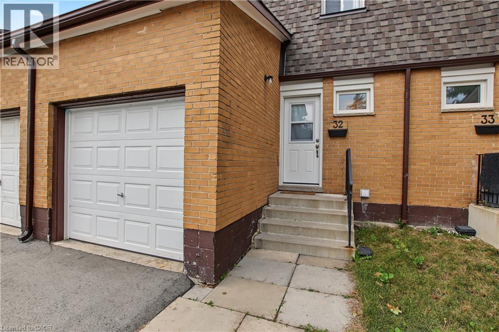 Brick exterior with an attached garage, paved driveway, and concrete steps leading to the front entry - 1444 Upper Ottawa Street Unit# 32, Hamilton, ON