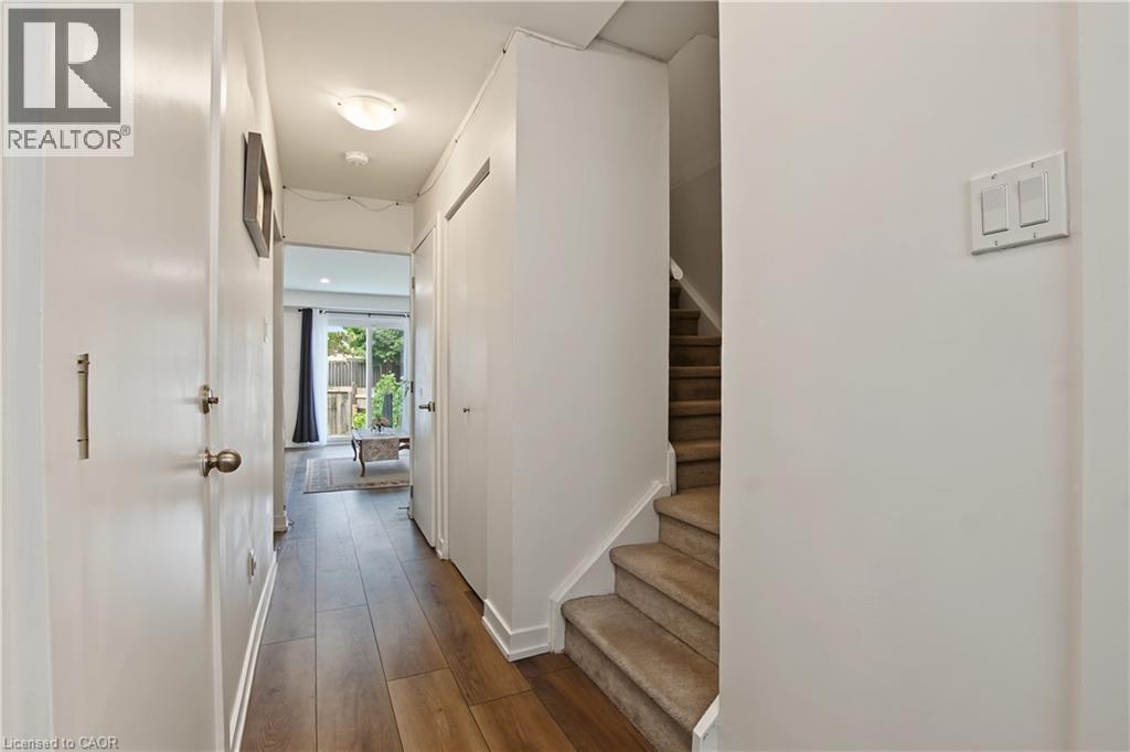 Hallway with wood-finish flooring, flush mount lighting, and a staircase with carpeted treads - 1444 Upper Ottawa Street Unit# 32, Hamilton, ON