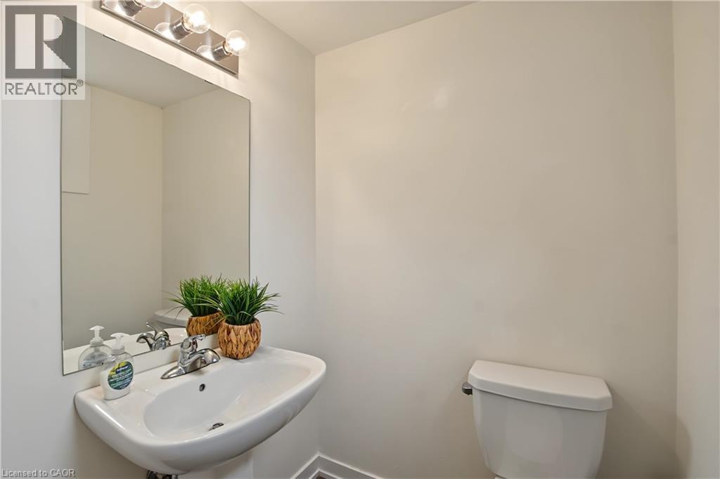 Pedestal sink with chrome faucet, wall-mounted mirror, and vanity lighting - 1444 Upper Ottawa Street Unit# 32, Hamilton, ON