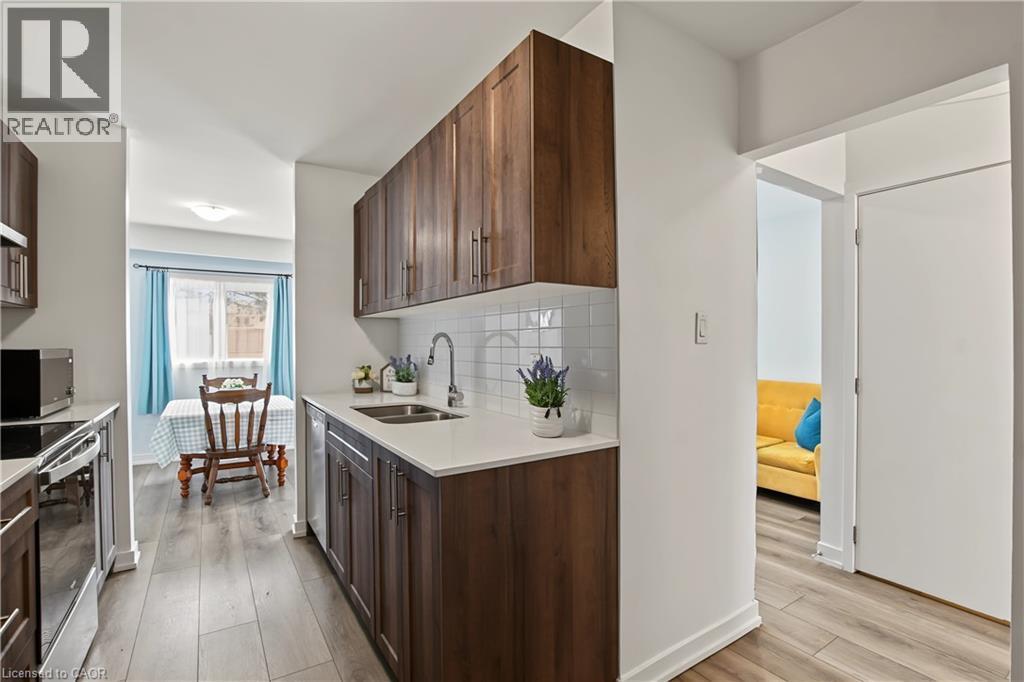 Galley kitchen featuring wood-finish cabinetry, white countertops, and a white subway tile backsplash - 1444 Upper Ottawa Street Unit# 32, Hamilton, ON