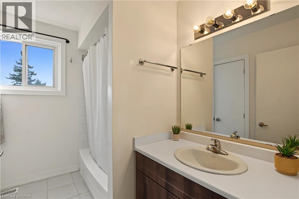 Bathroom featuring a vanity with an integrated sink, a large wall mirror, and a chrome light fixture - 1444 Upper Ottawa Street Unit# 32, Hamilton, ON