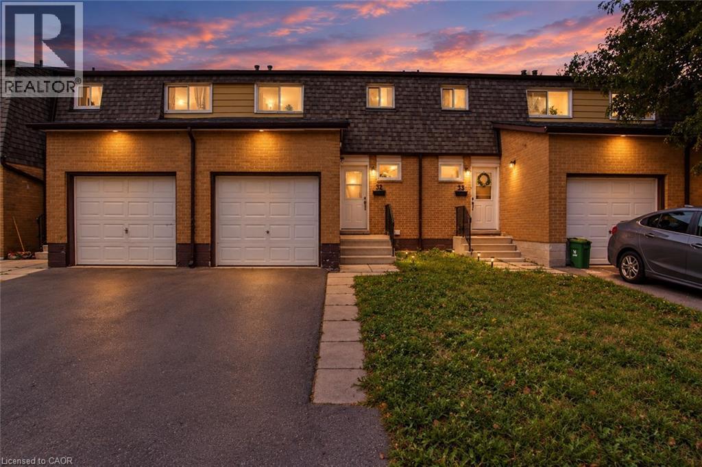 Brick facade, dormer windows, attached garages, paved driveways, and front entry stairs - 1444 Upper Ottawa Street Unit# 32, Hamilton, ON