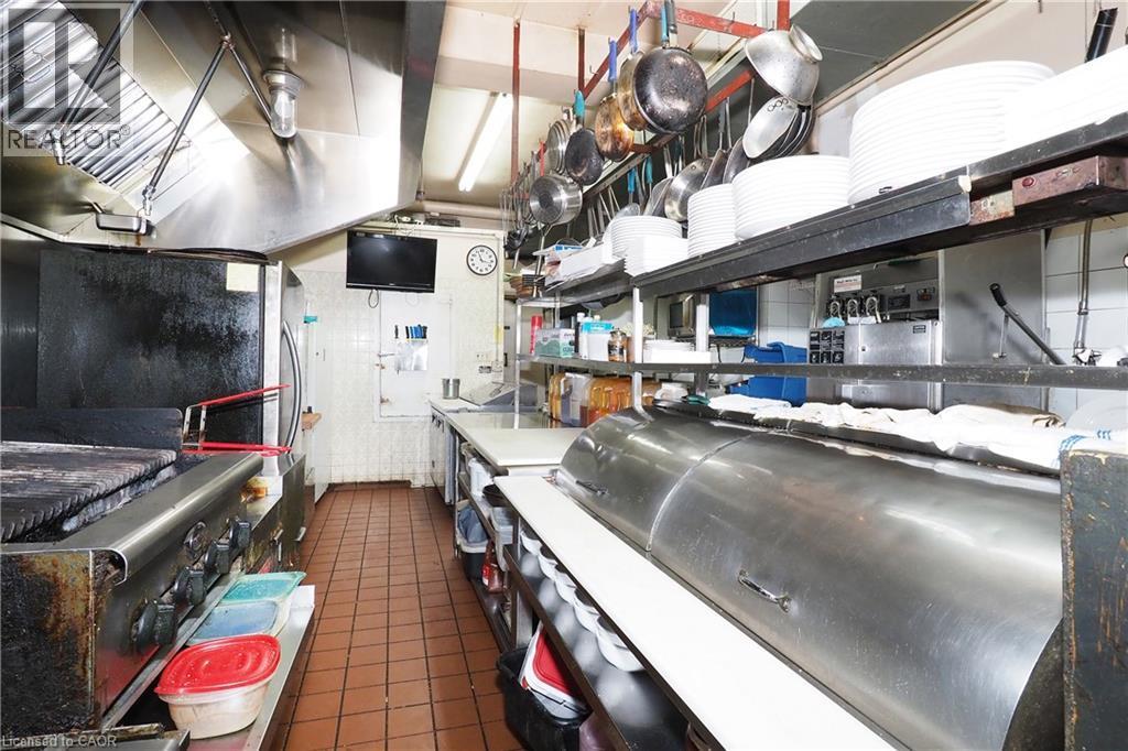 Commercial kitchen featuring stainless steel appliances, extensive counter space, and tiled flooring - 707 E King Street E, Cambridge, ON