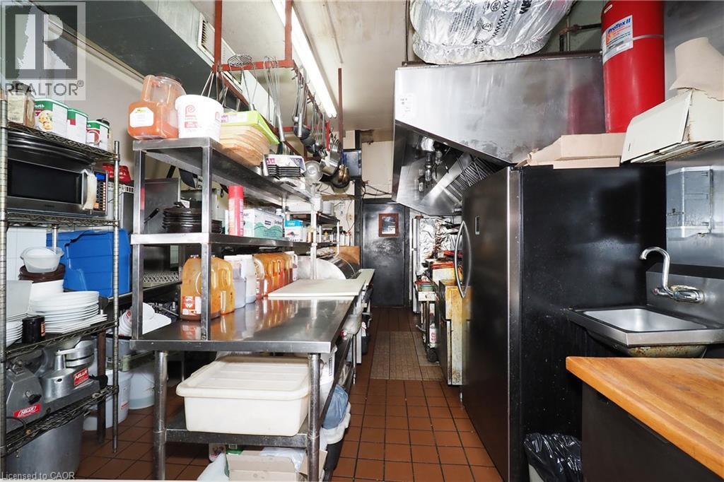 Commercial kitchen with tile flooring, stainless steel shelving, stainless steel countertops, and a built-in sink with a chrome faucet - 707 E King Street E, Cambridge, ON