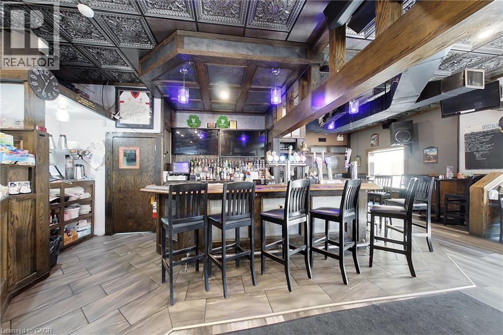Detailed patterned ceiling, wood-finish flooring, built-in wooden bar, integrated overhead lighting, and multiple mounted screens - 707 E King Street E, Cambridge, ON