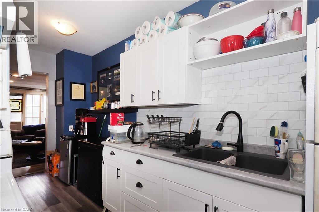 White cabinetry with black hardware, stone-finish countertops, black sink, and a white subway tile backsplash - 707 E King Street E, Cambridge, ON
