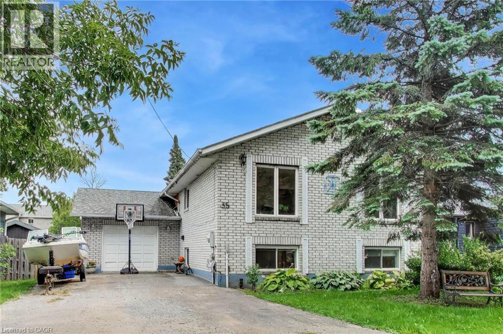 White brick exterior, attached two-car garage, established front landscaping, and a mature evergreen tree - 35 Shirlea Boulevard, Keswick, ON