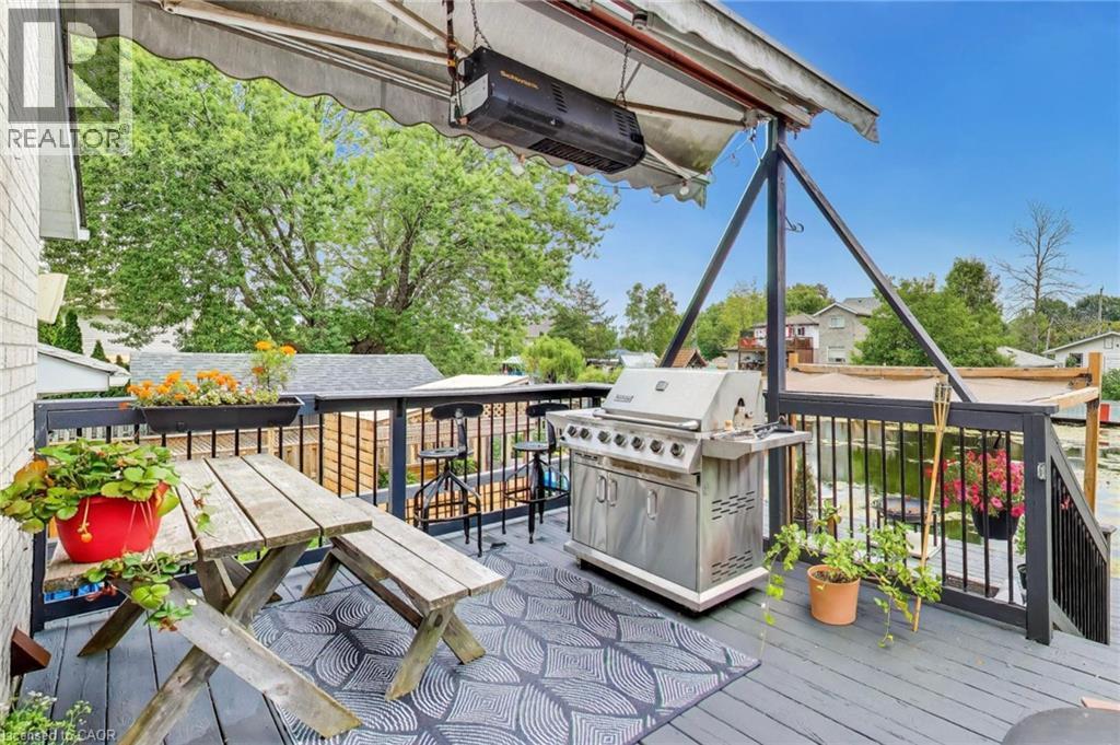Expansive outdoor deck with a retractable awning, dark railing, and a built-in outdoor grill - 35 Shirlea Boulevard, Keswick, ON