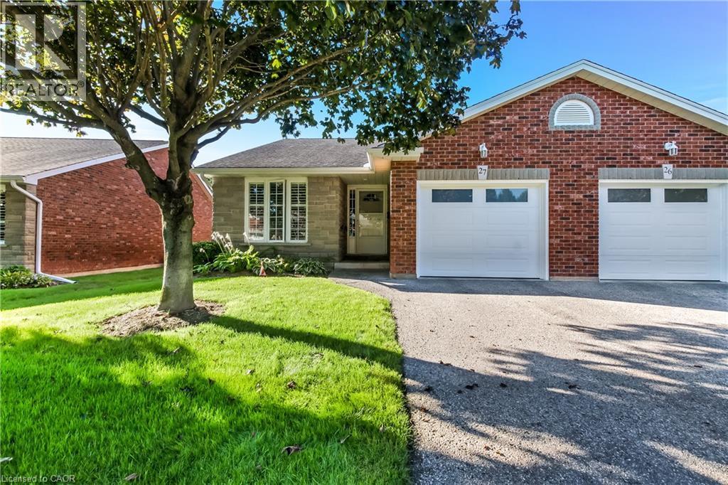 Brick and stone exterior with a single garage, manicured lawn, and a paved driveway - 150 Oak Street Unit# 27, Simcoe, ON