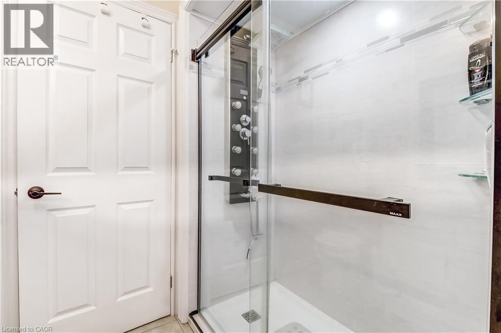 Glass-enclosed shower with a multi-function jet system shower panel, contemporary tile surround, and integrated glass shelving - 150 Oak Street Unit# 27, Simcoe, ON