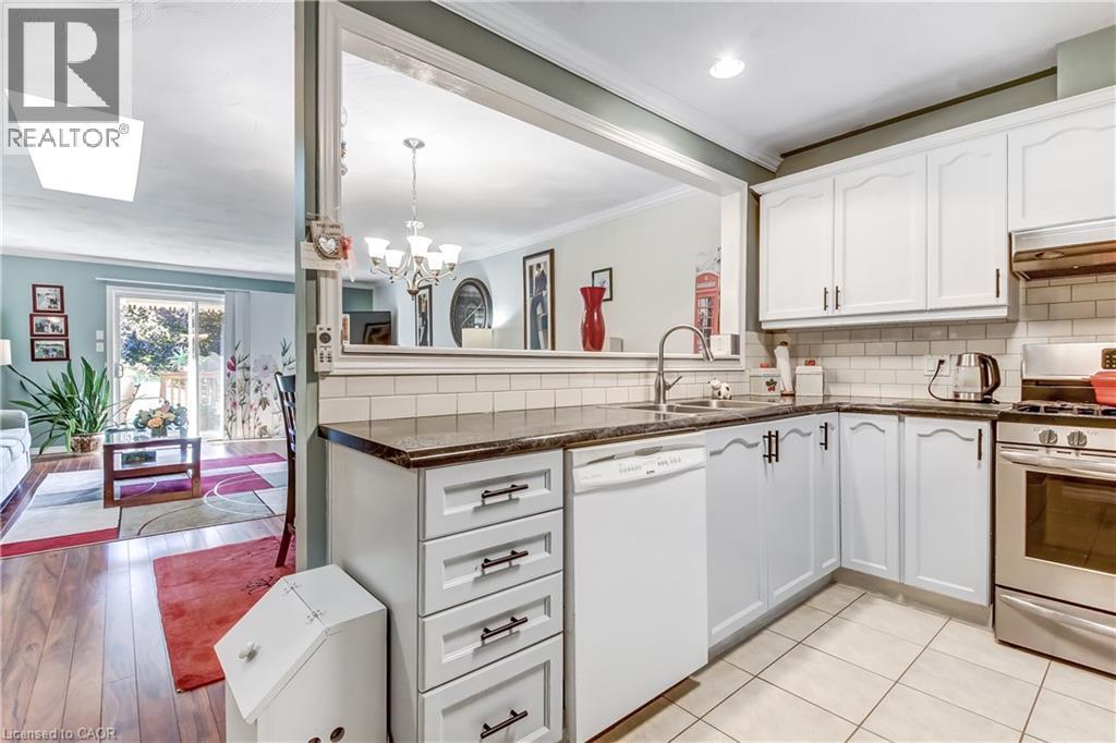 White cabinetry with dark hardware, stainless steel appliances, tile flooring, and a subway tile backsplash - 150 Oak Street Unit# 27, Simcoe, ON