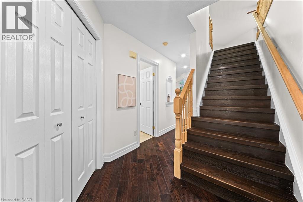 Wood-finish flooring, white paneled doors, dark wood staircase, wood handrail, recessed lighting - 495 Brigantine Drive, Waterloo, ON