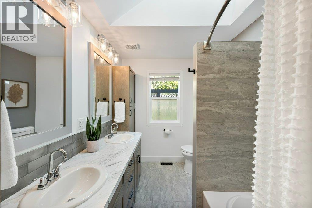 Main bath with dual vanities, tiled tub/shower surround - 886 Fairview Road, Oliver, BC