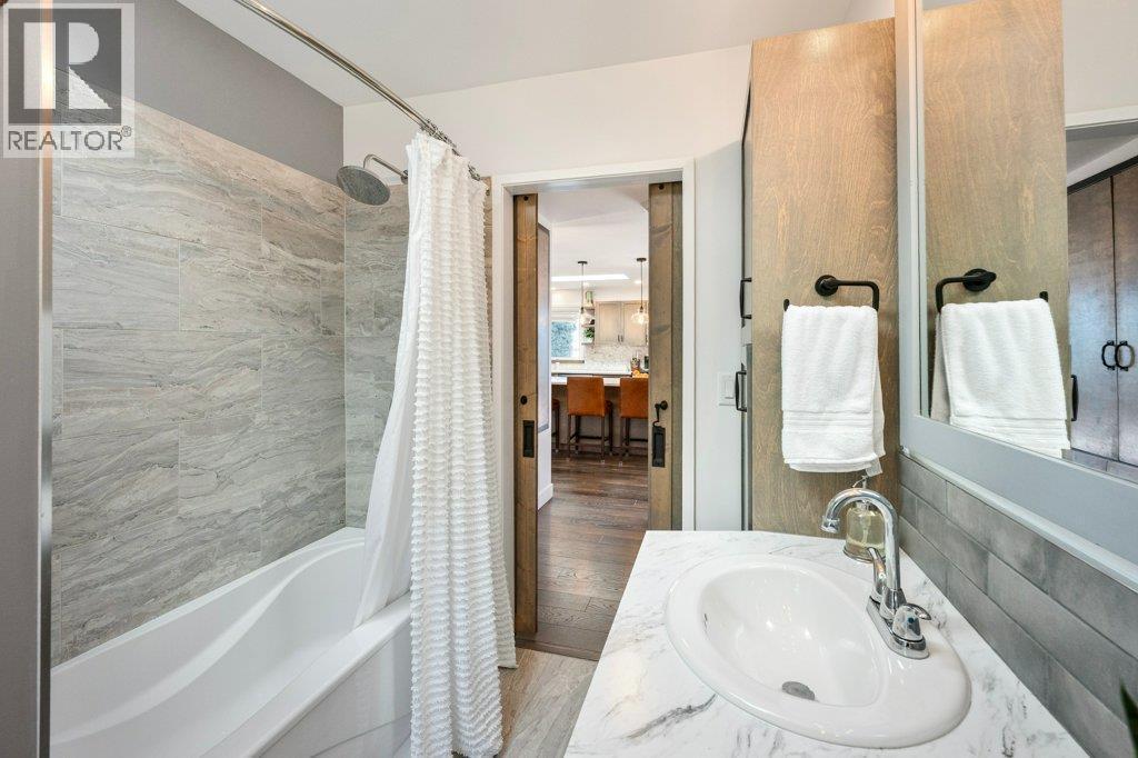 Main bath with dual vanities, tiled tub/shower surround, barn doors - 886 Fairview Road, Oliver, BC