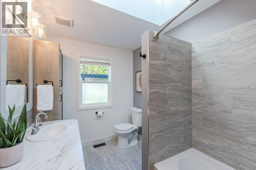 Main bath with dual vanities, tiled tub/shower surround - 886 Fairview Road, Oliver, BC