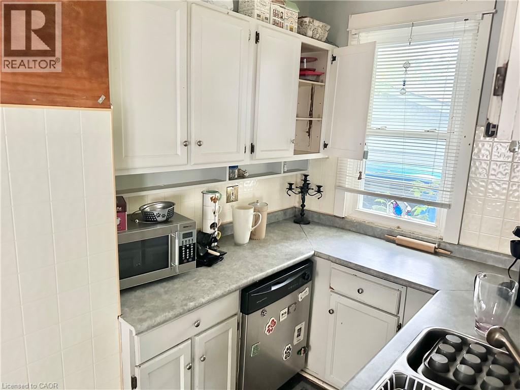 White cabinetry, stainless steel dishwasher, tile backsplash, and a single basin sink - 128 Kent Street S, Simcoe, ON