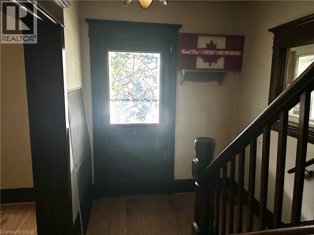 Entryway featuring a stained glass door, wood-finish flooring, and a dark wood staircase with balusters - 128 Kent Street S, Simcoe, ON