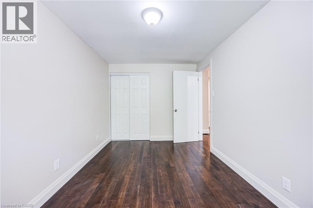 Dark wood-finish flooring, white walls, white trim, white bi-fold closet doors, and a ceiling-mounted light fixture - 2037 Mountain Grove Avenue, Burlington, ON