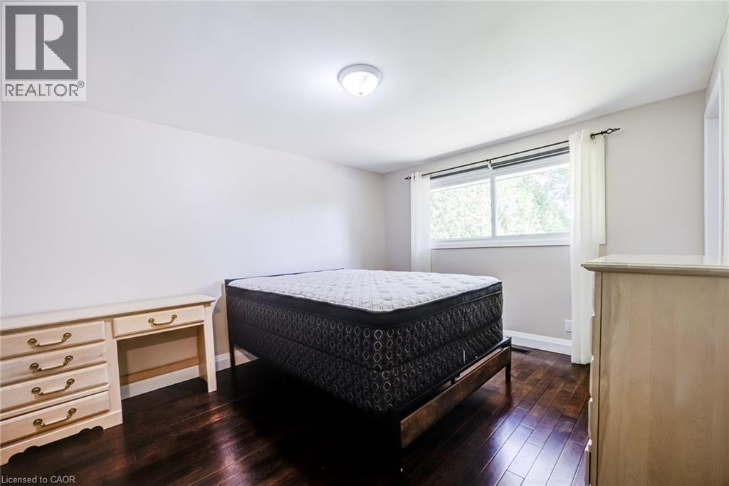 Dark wood-finish flooring with a ceiling-mounted light fixture and a window featuring white trim - 2037 Mountain Grove Avenue, Burlington, ON