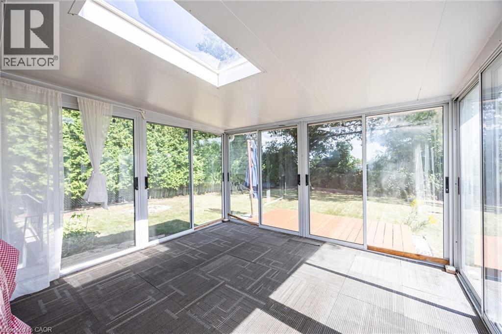 Sunroom with multiple sliding glass doors, a skylight, and patterned carpet flooring - 2037 Mountain Grove Avenue, Burlington, ON
