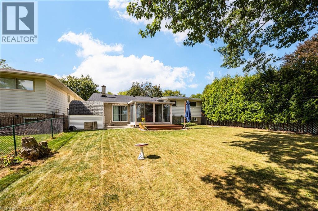 Expansive backyard with a manicured lawn, wood deck, and tall privacy hedges - 2037 Mountain Grove Avenue, Burlington, ON