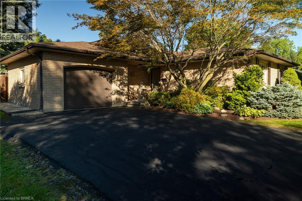 Brick exterior with a brown garage door, asphalt driveway, and established landscaping - 78 Berkley Crescent, Simcoe, ON