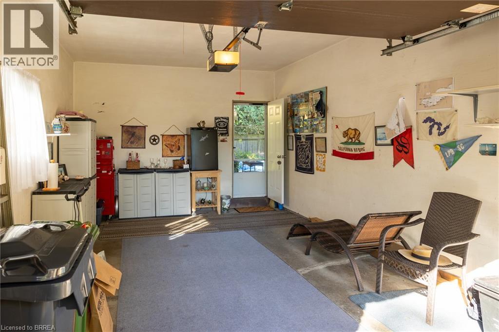 Garage space with concrete flooring, overhead lighting, and an exterior door providing outdoor access - 78 Berkley Crescent, Simcoe, ON