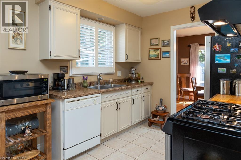 Kitchen featuring white cabinetry, granite-style countertops, an undermount sink, and tiled flooring - 78 Berkley Crescent, Simcoe, ON