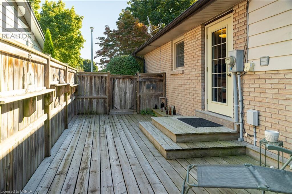 Private wood-plank deck with multi-level steps, framed by a wood privacy fence and featuring a single light-paneled door - 78 Berkley Crescent, Simcoe, ON