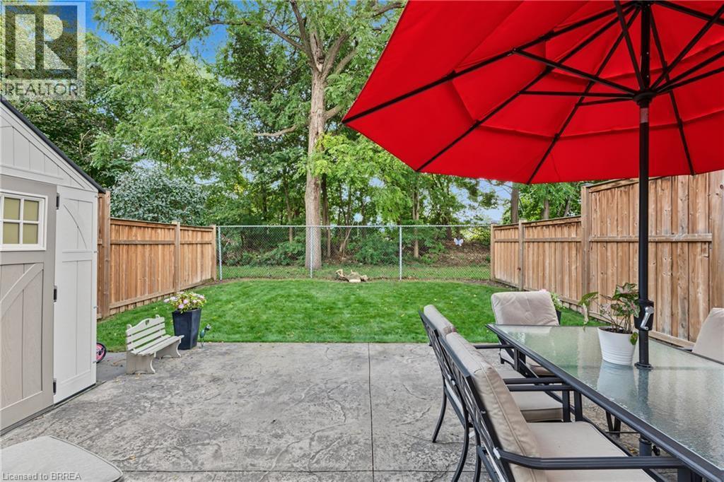 Stamped concrete patio with a detached storage shed, a manicured lawn, and wood privacy fencing - 332 Grand River Avenue, Brantford, ON