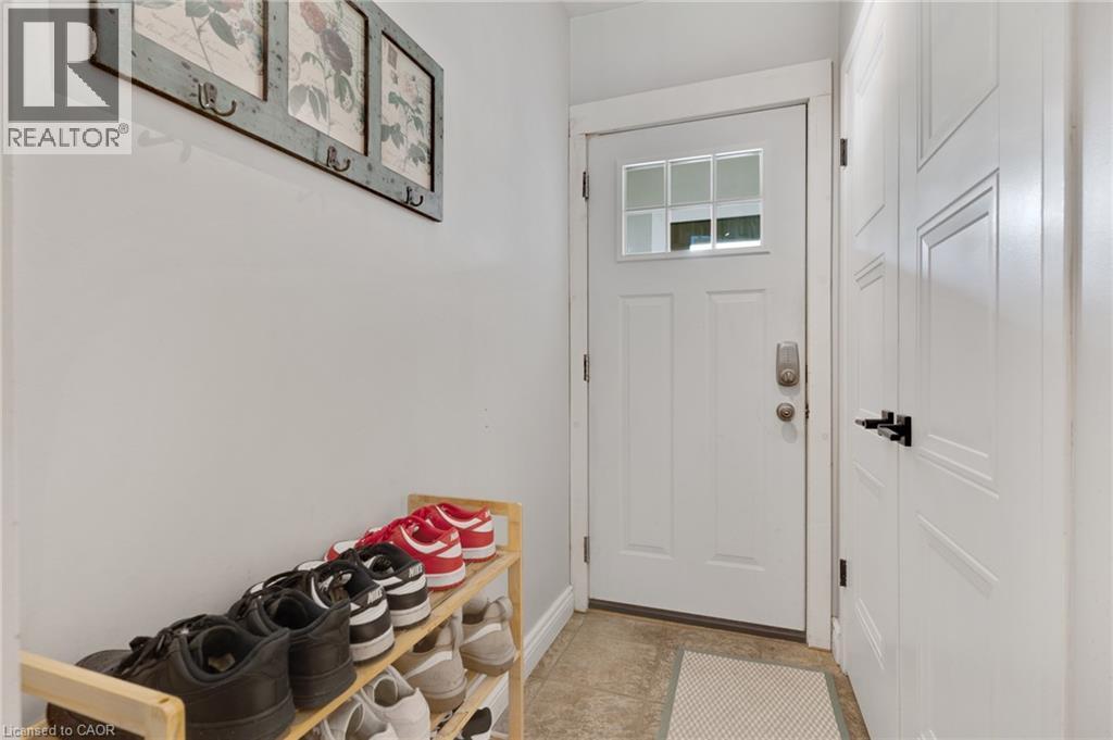 White paneled entry door with decorative glass inserts, smart lock system, and tile flooring - 7 Shadywood Lane, Cambridge, ON