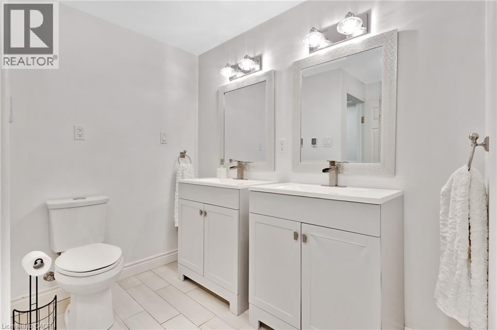 Dual white vanities with integrated sinks, framed mirrors, and matching wall-mounted light fixtures - 7 Shadywood Lane, Cambridge, ON