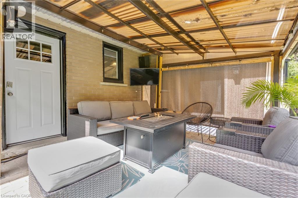 Covered outdoor patio featuring a brick wall, white exterior door with window panes, and a mounted outdoor light fixture - 7 Shadywood Lane, Cambridge, ON