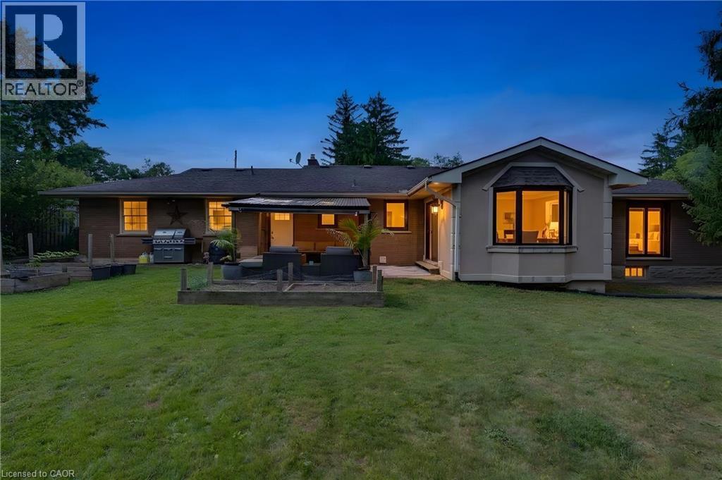 Expansive lawn with a bay window, brick and stucco exterior, and a rear patio - 7 Shadywood Lane, Cambridge, ON