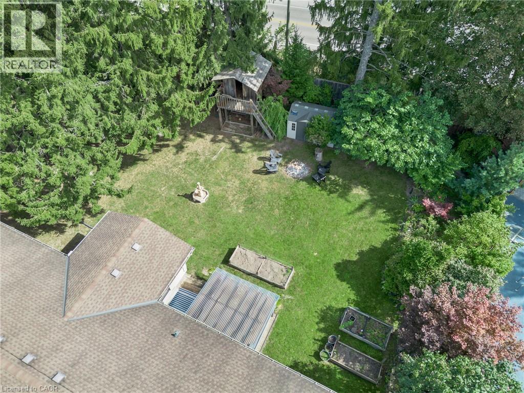 Expansive backyard featuring a lush lawn, mature trees, a detached storage shed, and raised garden beds - 7 Shadywood Lane, Cambridge, ON