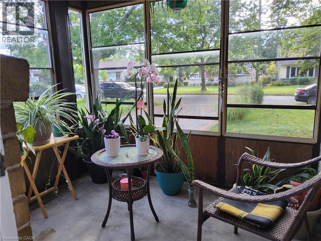 Enclosed porch featuring full-length windows, concrete flooring, and wood-paneled lower walls - 33 Lee Avenue, Simcoe, ON