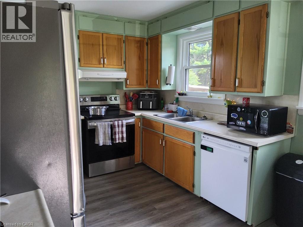 Kitchen featuring wood-finish flooring, stainless steel appliances, dual basin sink, and wood cabinetry - 33 Lee Avenue, Simcoe, ON